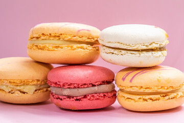 Obraz na płótnie Canvas Colorful french cookies macarons set on pink background. Tasty fruit, almond sweet cookies, cake macaron