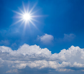 Naklejka na ściany i meble sparkle sun above dense cumulus clouds on the blue sky background, summer concept scene
