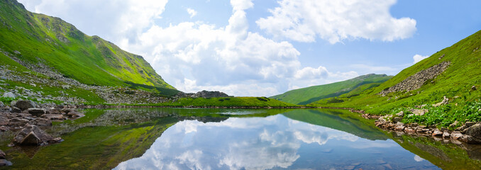 Fototapeta na wymiar calm lake in the green mountain bowl, summer hiking scene