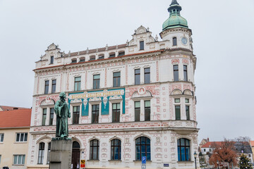 Fototapeta na wymiar Neo-Renaissance white building of the former Farmers' bank Podripska with red sgraffito mural decorated plaster and statue of Jan Hus in Roudnice nad Labem, Bohemia, Czech Republic