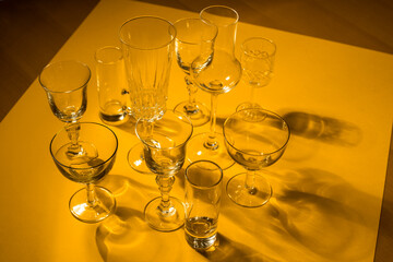 Different types of empty glasses on yellow background