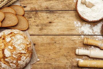 Fresh bread with wheat ears and a bowls of flour and grain, rolling pins