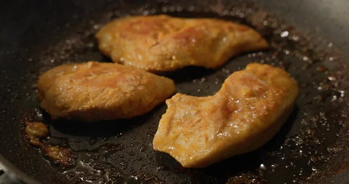 preparing chicken breast fillet on frying pan closeup
