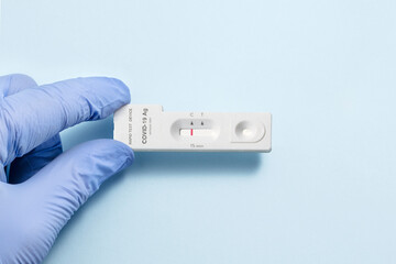 A hand in a blue glove shows how a device to perform a covid 19 sars test gives a negative result
