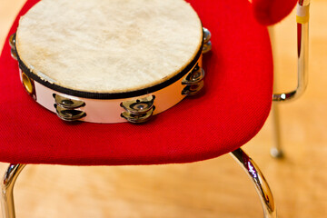 Tambourine on a red chair. Percussion instrument on stage.