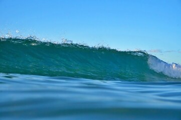 A wave breaks in crystal clear waters on a sunny day on the Sunshine Coast