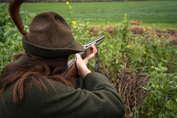 Auf der Jagd - junge Jägerin zielt mit ihrem Gewehr auf einen Fuchs, jagdliches Symbolfoto. - obrazy, fototapety, plakaty
