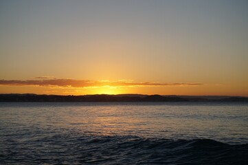 A wave rolls towards the shore at sunset - Gold Coast