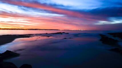 Fototapeta na wymiar Long Exposure - A colourful sunset bathes the ocean in bright colours at Snapper Rocks at high tide - Gold Coast