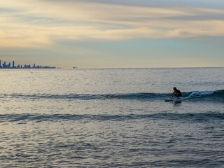 A surfer crouched down riding a small wave at Snapper Rocks by himself - Australia