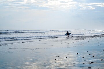 A surfer walking into the warm Balinese waters