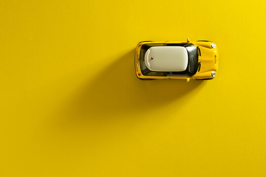 Top view of a Mini Cooper S Yellow toy car on a yellow background with a long shadow
