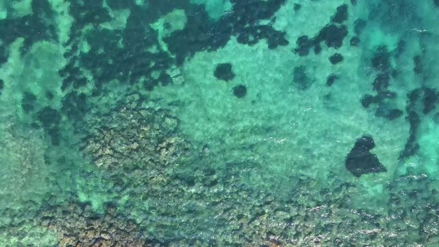 Drone fly up above transparent, clear sea water. Aerial view of azure water. Stones in the sea