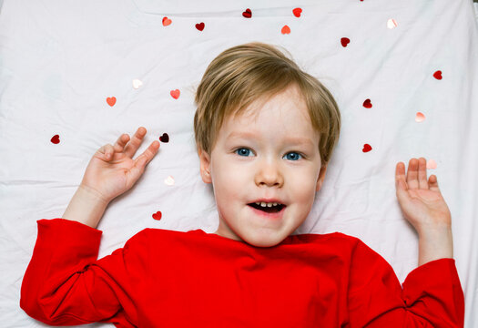 A kid todder child lies on a bed with hearts. Concept of first love and valentine's in kindergarten and school.