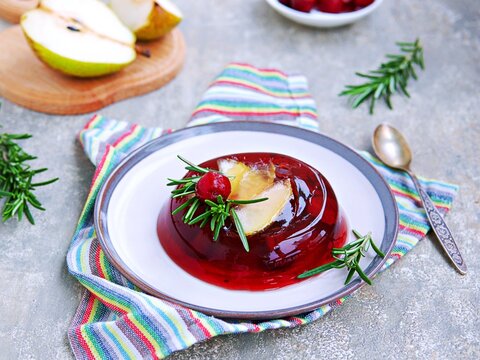 Dessert, cherry jelly with pear on a ceramic plate on a gray concrete background. Jelly recipes.