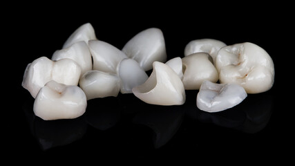 a set of different dental veneers in a chaotic manner, on black glass with reflection