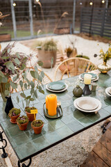 Festively decorated tablescape in green tones with candles, herbs and flowers in a natural Boho style outdoors
