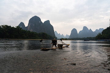 Cormorant fishermen at the river side at dusk  in Xingping China 