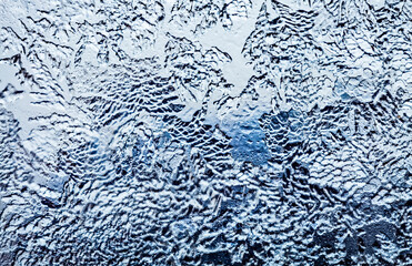 Frosty pattern on the window close up selective focus. Dark blue tone. Winter evening background.