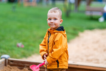 Nephew Holding Pink Toy Shovel, Standing in Sandbox on Playground
