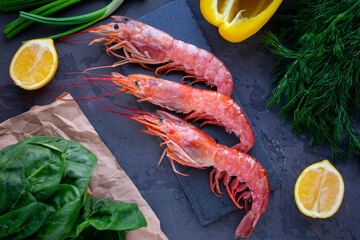 Large langoustines shrimp on a black stone on the black kitchen table. Seafood for a healthy diet. Ingredients. Top view.