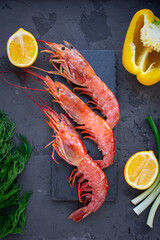 Large langoustines shrimp on a black stone on the black kitchen table. Seafood for a healthy diet. Ingredients. Top view.