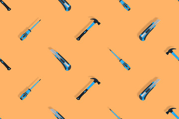 Tools seamless pattern. Tools: hammer, screwdriver and knife on an orange background.