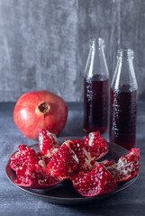 Cut ripe pomegranate into pieces and freshly squeezed pomegranate juice in two bottles on a dark...