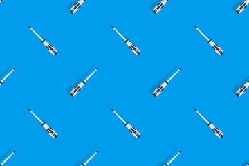 Screwdrivers seamless pattern. Metal screwdrivers with a rubberized handle on a blue background.