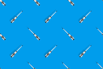 Screwdrivers seamless pattern. Metal screwdrivers with a rubberized handle on a blue background.