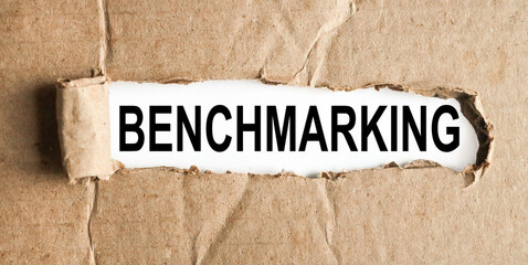 BENCHMARKING, text on white paper on torn paper background