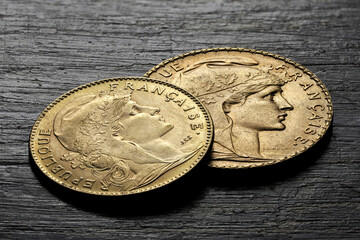 French 10 and 20 Francs gold coins (obverse with Marianne) on rustic wooden background