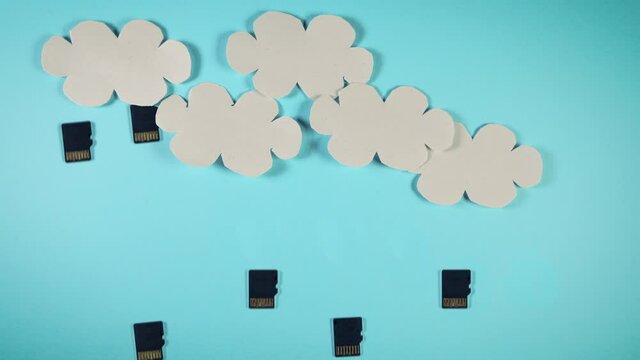 Cloud computing concept, paper clouds with micro SD memory cards as raindrops on a blue background