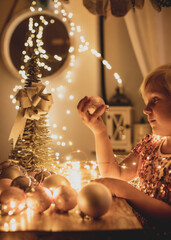 pretty,blonde child,girl in romantic christmas mood with lights and christmas balls 