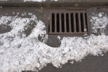 1 - Melting snow flows into an iron kerbside surface drain.