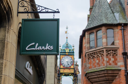 Clarks shop sign and the famous Chester Eastgate Clock at the background. The High street, Chester, United Kingdom.