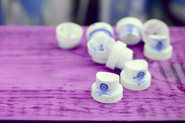 The soiled blue nozzles from the paint sprayer lies on a purple plank on a background of a many...