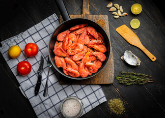 Raw Northern shrimps or prawns with vegetables in a frying pan . Top view