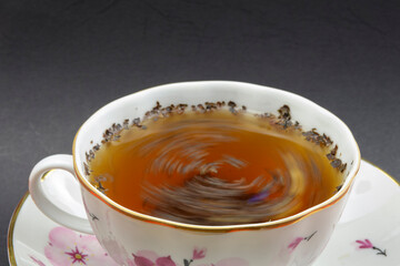 Ceramic cup with black tea. Tea leaves in it.