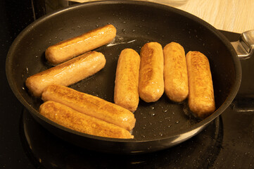 A pan of sausages frying in a pan