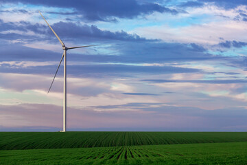 wind power generator in green hilly landscape in the background sky with clouds, zero emissions...