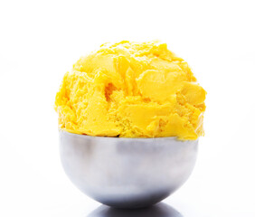 A ball of natural mango ice cream in a spoon. Tropical orange ice cream on a white