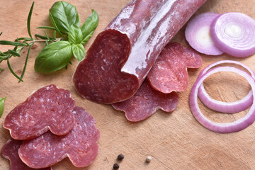 Slices of delicious spanish sausage fuet on the wooden natural kitchen board closeup. Love food concept. Traditional Spanish sausage. Variety of dry cured chorizo. Heart shaped sausage.