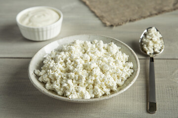 Dairy products sour cream, cottage cheese in white utensils on white wooden background close up. Natural, organic food.