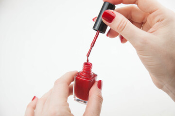 Girl paints nails with red varnish on a white background. close-up
