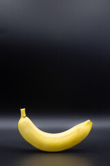 Unpeeled healthy banana free standing against a black background