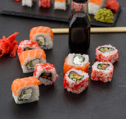 california sushi with red tobiko caviar and slices of philadelphia sushi on black slate board