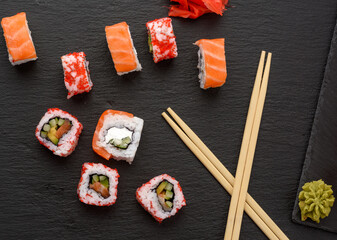 california sushi with red tobiko caviar and slices of philadelphia sushi on black slate board