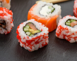california sushi with red tobiko caviar and slices of philadelphia sushi on black slate board
