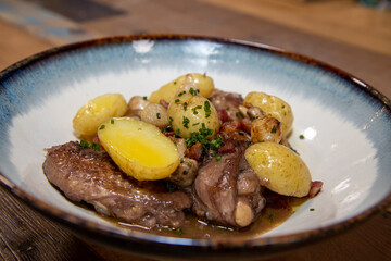 A delicious plate of chicken coq au vin with potatoes on a wooden kitchen work top